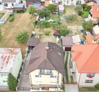 Family houses in Medzibrod with gardens and surrounding greenery in an aerial view.