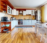 A kitchen in a family house with white furniture and a wooden decor floor.