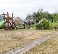 The courtyard of a family house in Medzibrod with a wooden climbing frame set and a garden.