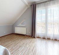 A room in a family house with a wooden decor floor and a view through a large window.