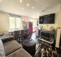 Living room with a TV, sofa, and shiny wooden-decor floor in a 4-room apartment.