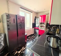A kitchen in a 4-room apartment with a dark wood-patterned floor and colorful cabinets.