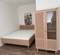 Bed, wardrobe, and floor with wood decor in a studio apartment.