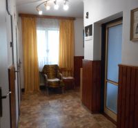 A hallway in a family house with a wooden decor floor, an armchair, and curtains.
