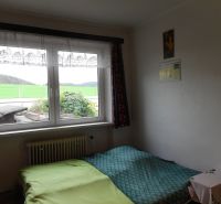 A room with a green bed, a window, and a view. The family house offers a cozy space.