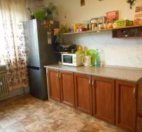 A kitchen in a family house with a refrigerator and cabinets, a floor with a wooden decor.