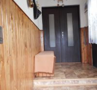 A hallway in a family house with wooden paneling and ceramic flooring.