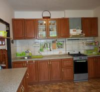 A kitchen in a family house with brown cabinets, tiles, and a gas stove.