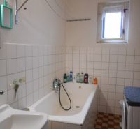 A bathroom in a family house with a bathtub, a washing machine, and a window.