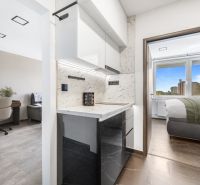 A kitchen with a marble countertop, next to a desk on a floor with a wooden decor.