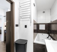 A bathroom in a 2-room apartment with a bathtub and dark tiles.