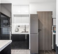A kitchen in a 2-room apartment with white and black cabinets.