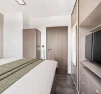 A bedroom with a bed, wardrobe, and television in a 2-room apartment.