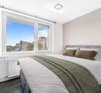A bedroom in a 2-room apartment with a large window and a comfortable bed.