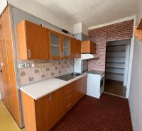 A kitchen in a 3-room apartment with tiles, a kitchen unit, and a brick-patterned wallpaper.