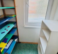 Storage space in a 3-room apartment with shelves and a window, floor with decor.