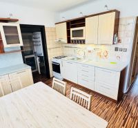 A kitchen with a dining table in a 3-room apartment with a wooden decor floor.