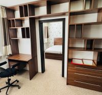 A workspace with shelves in a 3-room apartment, leading to the bedroom.