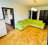 Living room with a green sofa and a wooden decor floor in a 3-room apartment.