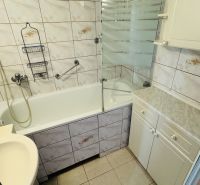 A bathroom in a 3-room apartment with a bathtub, a sink, and a cabinet.