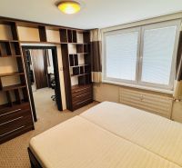 A bedroom with shelves in a 3-room apartment, equipped with a large window with blinds.