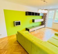 Living room with a colorful wall, green sofa, and wooden decor flooring.
