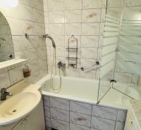 A bathroom in a 3-room apartment with a bathtub, a sink, and tiles.