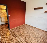 A room in a 3-room apartment with a wooden decor floor and a wall in a warm color.