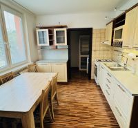 A kitchen with a wooden decor floor in a 3-room apartment, a dining table by the window.