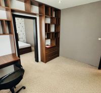 A room in a 3-room apartment with a desk, chair, and entrance to the bedroom.