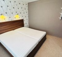 A bedroom in a 3-room apartment with simple decoration and floral patterned wallpaper.