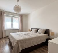 Bedroom in a 2-room apartment with a wooden decor floor and white walls.