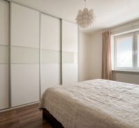Bedroom in a 2-room apartment with a large wardrobe, bed, and floor with a wooden decor.