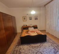 Bedroom in a family house with a bed, cabinet, carpet, and wall decorations.