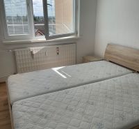 A bed with orthopedic mattresses and a floor with a wooden decor in a studio apartment.