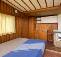 Wooden interior with a bed, stove, and curtains in the garden.