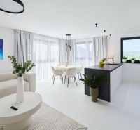 Bright living room with a kitchen in a 4-room apartment, large windows and curtains.