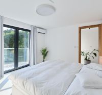 A bright bedroom with a bed, balcony, and plant in a 4-room apartment.