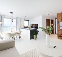 The living room of a 4-room apartment with an elegant table, kitchen, and a television on a wooden wall.