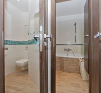 A bathroom in a three-room apartment with a wooden decor floor and modern sanitary ware.
