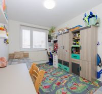Children's room with a bed, colorful carpet, and shelving storage system in a 3-room apartment.