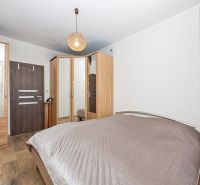 A bedroom in a 3-room apartment with a wood-decor floor, a wardrobe, and mirrors.