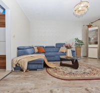 Living room with a sofa, glass table, and wooden decor flooring in a 3-room apartment.