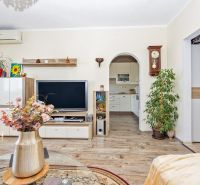 Living room with a TV, wood-decorated floor, and flowers in a 3-room apartment.