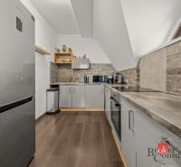 A kitchen with appliances and a wooden decor floor in a 4-room apartment.