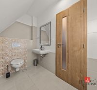 Bathroom with a wall-mounted toilet, sink, and wooden door in a 4-room apartment.