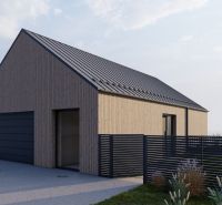 A family house in Staškov with wooden cladding and a black roof, with a lawn and a fence nearby.
