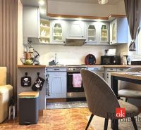 A kitchen in a 3-room apartment with a wooden decor floor and grey cabinets.