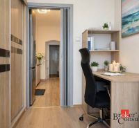 A workspace in a 3-room apartment with a wooden decor floor and office furniture.