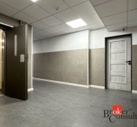 A hallway with gray tiles, an elevator, and doors in a 3-room apartment.